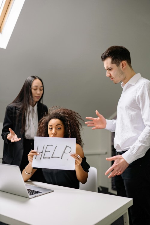 A Women with a HELP placard in the office.